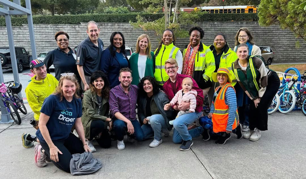 Photo by Matt Westmoreland in Burgess-Peterson Academy. May be an image of one or more people, people smiling, people standing, scooter, wheelchair, buggy, park and text.
